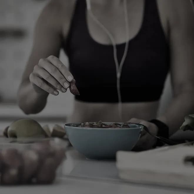 Someone preparing a bowl of fruit and vegetables on a kitchen board after training