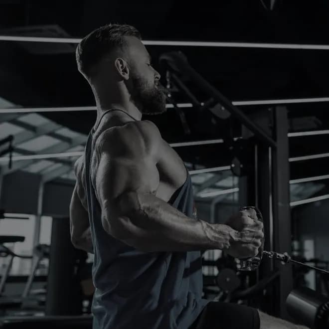 A lifter mid-repetition on a cable machine, side on, shoulders and back under load
